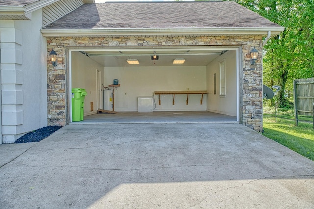 garage featuring electric water heater, driveway, and a garage door opener