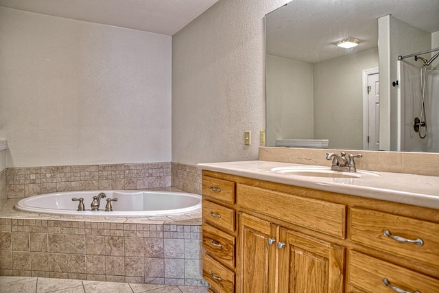 bathroom with a garden tub, tile patterned floors, a shower, a textured wall, and vanity
