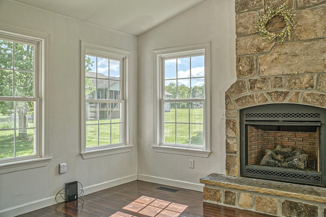 interior space featuring a large fireplace, lofted ceiling, a healthy amount of sunlight, and dark wood-style floors