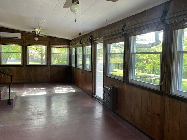 unfurnished sunroom featuring a wealth of natural light, wood walls, concrete floors, and an AC wall unit
