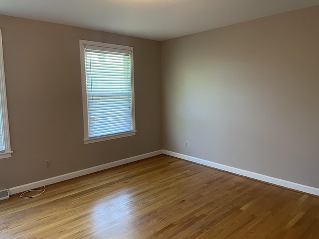 unfurnished room featuring baseboards, light wood-type flooring, and plenty of natural light