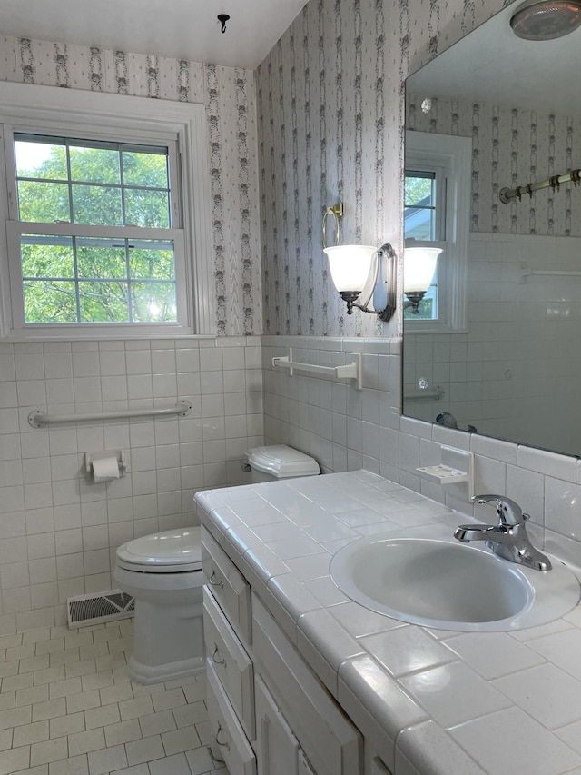 bathroom with wallpapered walls, a wealth of natural light, and visible vents