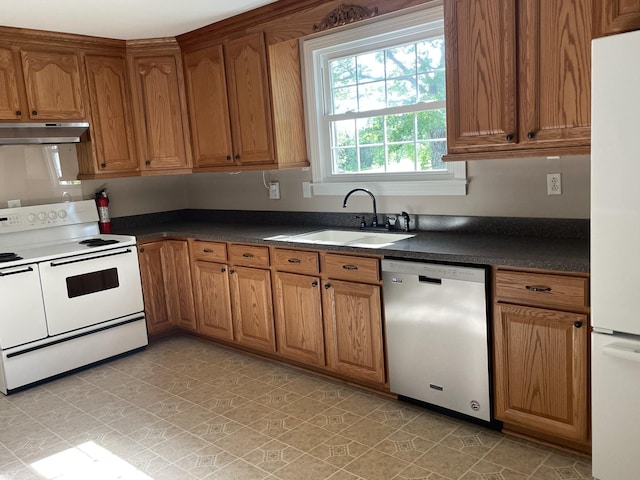 kitchen featuring under cabinet range hood, dark countertops, a sink, and white appliances