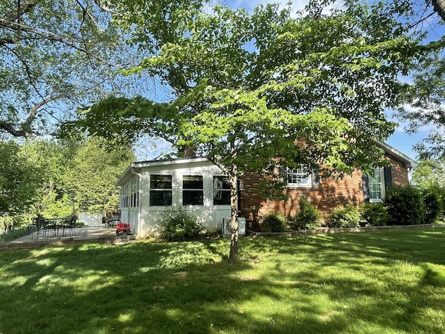 view of front of property featuring a patio area, brick siding, and a front yard