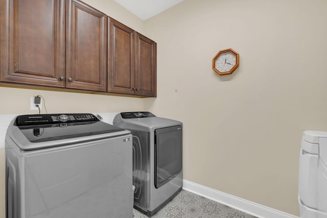 clothes washing area featuring baseboards, cabinet space, and washer and clothes dryer