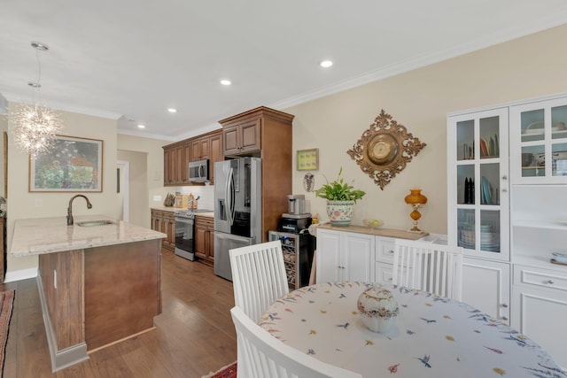 kitchen with stainless steel appliances, light stone counters, ornamental molding, and brown cabinets