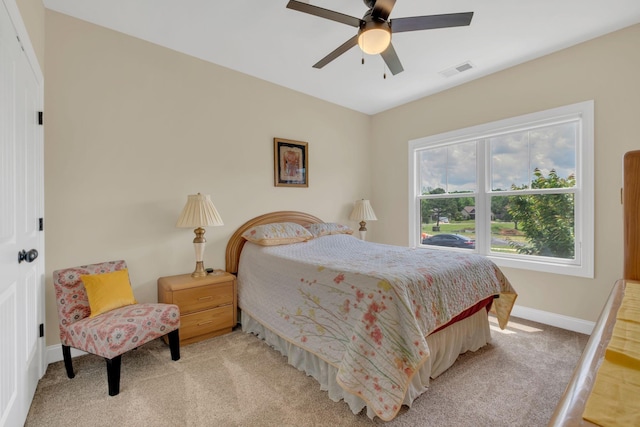 bedroom featuring baseboards, ceiling fan, visible vents, and light colored carpet