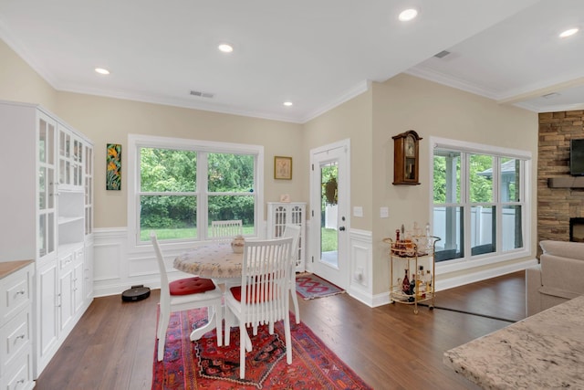 dining area featuring dark wood-style flooring, ornamental molding, visible vents, a decorative wall, and a wainscoted wall