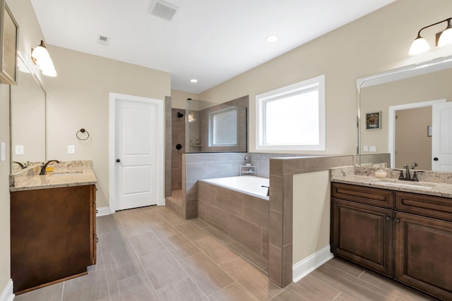 full bathroom featuring a sink, a walk in shower, a garden tub, and visible vents