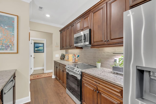kitchen with dark wood-style flooring, crown molding, decorative backsplash, baseboards, and appliances with stainless steel finishes