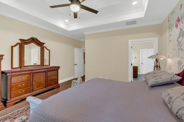 bedroom featuring a tray ceiling, ornamental molding, a ceiling fan, and wood finished floors
