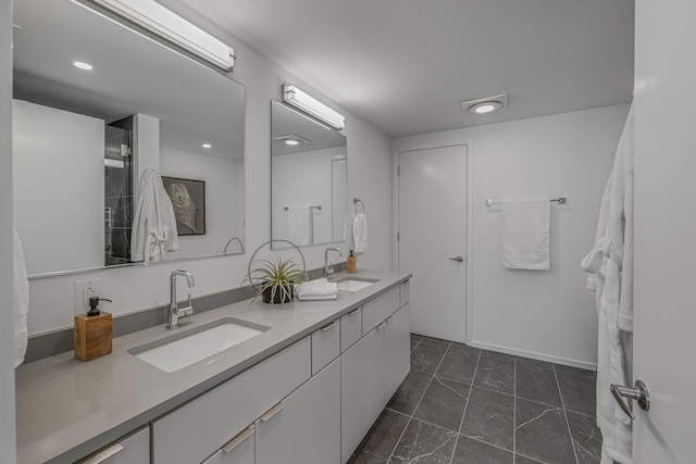 bathroom with marble finish floor, recessed lighting, double vanity, and a sink