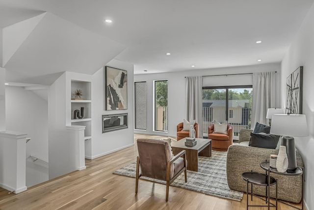 living area with light wood finished floors, recessed lighting, and built in features