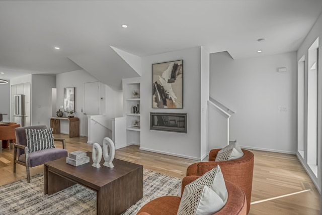living room with recessed lighting, baseboards, light wood-type flooring, and built in features