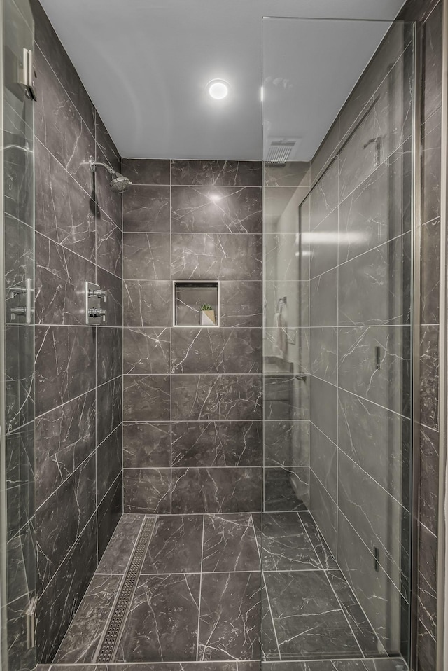 bathroom featuring marble finish floor, tiled shower, and recessed lighting