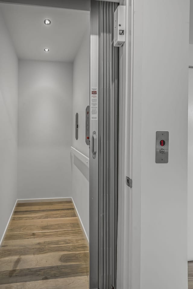interior details featuring elevator, wood finished floors, baseboards, and recessed lighting
