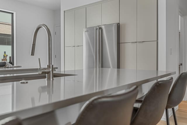 kitchen featuring a breakfast bar, freestanding refrigerator, light wood-type flooring, modern cabinets, and gray cabinetry