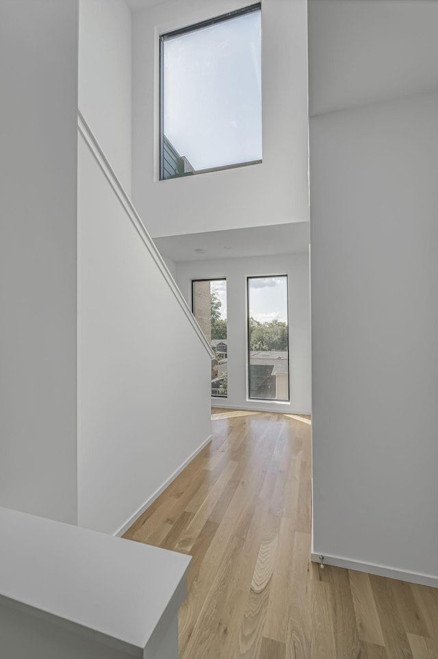 foyer with baseboards, stairs, light wood-type flooring, and a high ceiling