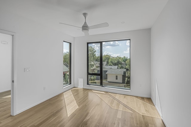 empty room featuring baseboards, wood finished floors, and a ceiling fan