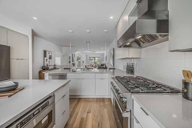 kitchen featuring a sink, stainless steel appliances, modern cabinets, and wall chimney exhaust hood