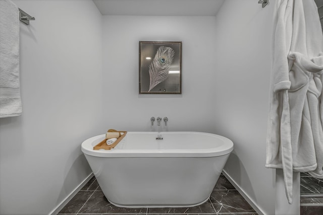 full bath featuring baseboards, marble finish floor, and a soaking tub