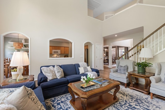 9404 Dove Field Ct, Brentwood, TN 37027 - living area featuring wood finished floors, a high ceiling, decorative columns, stairway, and arched walkways