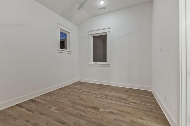 unfurnished room with lofted ceiling, wood finished floors, visible vents, a ceiling fan, and baseboards