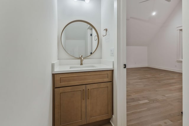 bathroom with wood finished floors, baseboards, ceiling fan, vaulted ceiling, and vanity