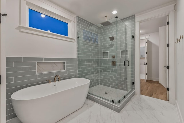 full bathroom with tile walls, a shower stall, a freestanding tub, marble finish floor, and recessed lighting