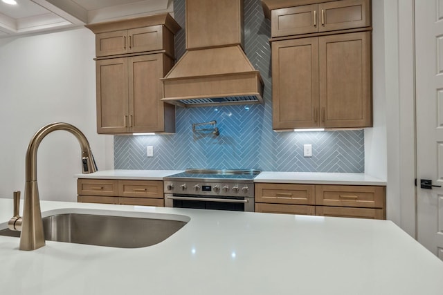 kitchen with high end stove, light countertops, custom range hood, and a sink