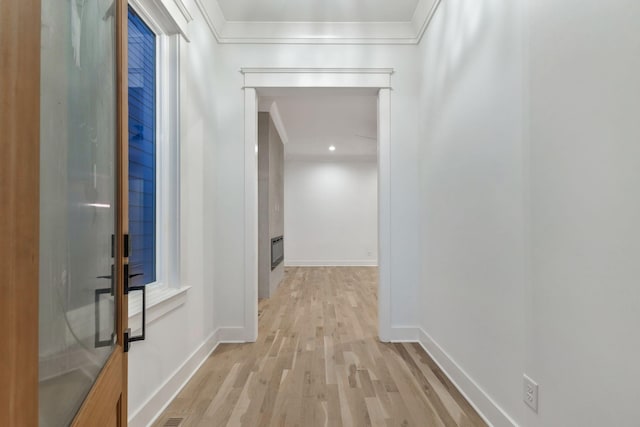 hall with baseboards, ornamental molding, and light wood-style flooring