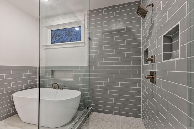 bathroom featuring wainscoting, a soaking tub, and tiled shower