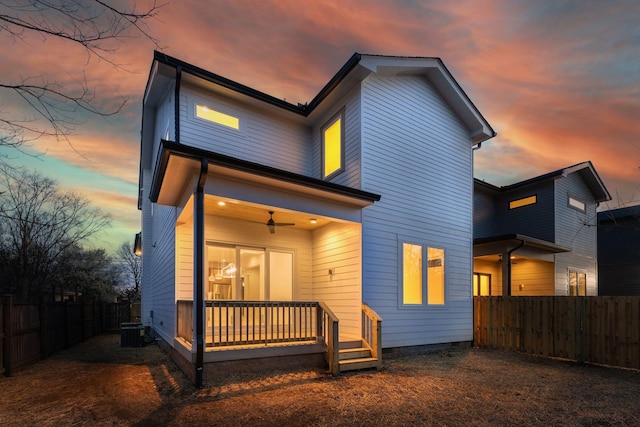 back of house at dusk featuring central AC unit, crawl space, fence private yard, and a ceiling fan