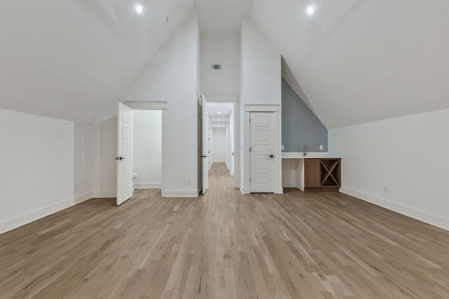 bonus room featuring baseboards, light wood-style floors, visible vents, and high vaulted ceiling