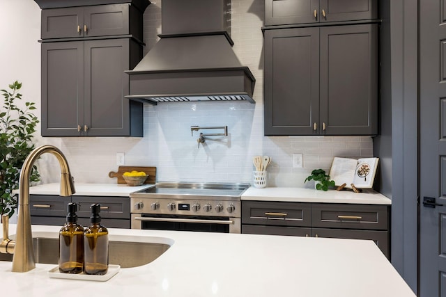 kitchen featuring a sink, electric range, backsplash, light countertops, and custom exhaust hood