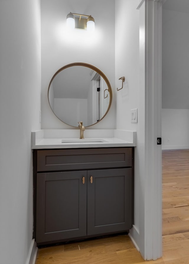 bathroom featuring baseboards, wood finished floors, and vanity