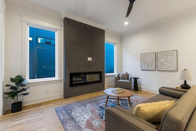 living area with baseboards, visible vents, crown molding, and wood finished floors
