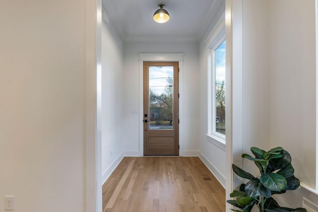doorway to outside featuring crown molding, light wood-style flooring, baseboards, and visible vents