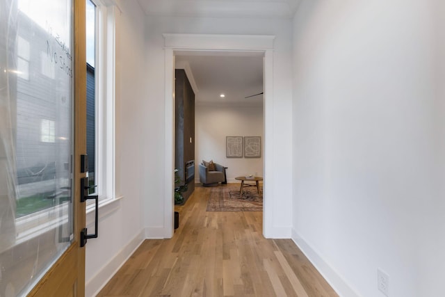 hallway featuring a wealth of natural light, baseboards, and light wood-type flooring