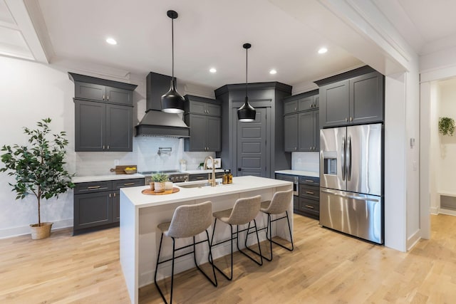 kitchen featuring baseboards, custom exhaust hood, appliances with stainless steel finishes, and a sink