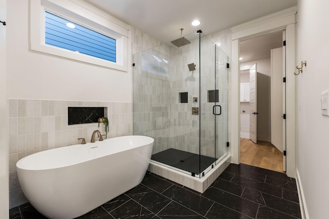 bathroom featuring a stall shower, a soaking tub, tile walls, marble finish floor, and recessed lighting