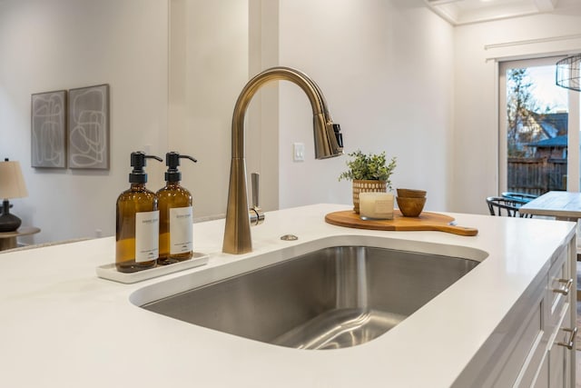 interior details with white cabinets, light countertops, and a sink