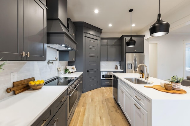 kitchen featuring premium range hood, light countertops, stainless steel appliances, and a sink