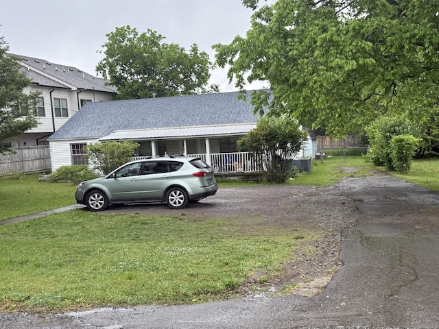 tri-level home featuring a shingled roof, driveway, fence, and a front yard
