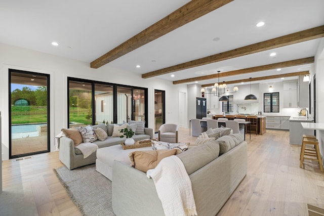 living area with light wood-style floors, beamed ceiling, visible vents, and recessed lighting