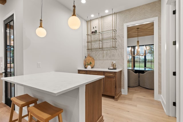 kitchen with a notable chandelier, pendant lighting, recessed lighting, a kitchen breakfast bar, and light wood-style floors
