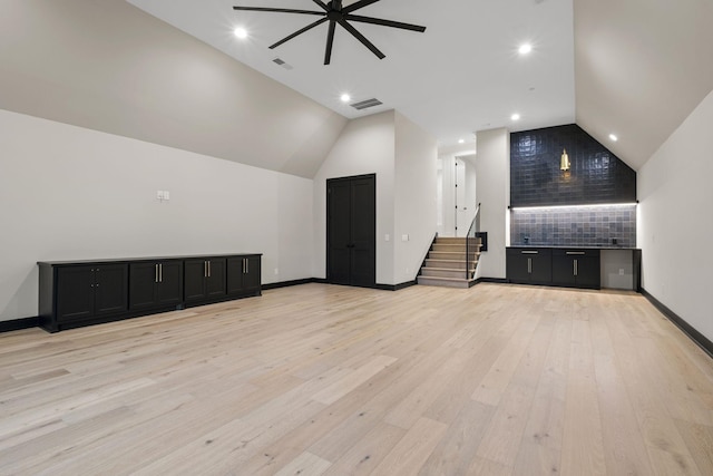 unfurnished living room with lofted ceiling, visible vents, stairway, ceiling fan, and light wood finished floors