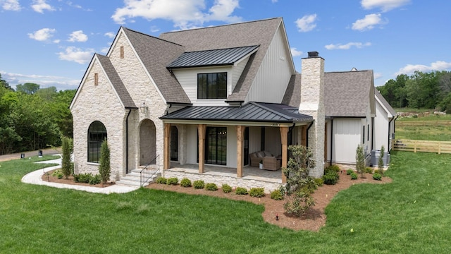 view of front of home featuring a front lawn, stone siding, a chimney, and a standing seam roof