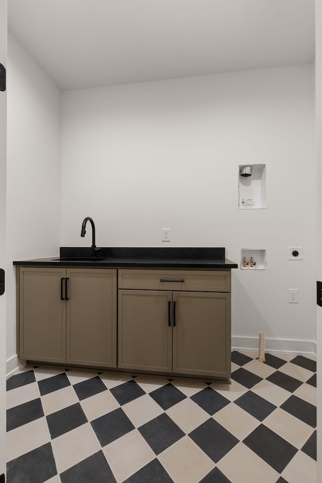 laundry area with light floors, hookup for a washing machine, a sink, hookup for an electric dryer, and cabinet space