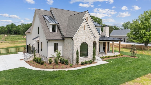 view of side of property featuring a lawn, a standing seam roof, fence, a shingled roof, and concrete driveway